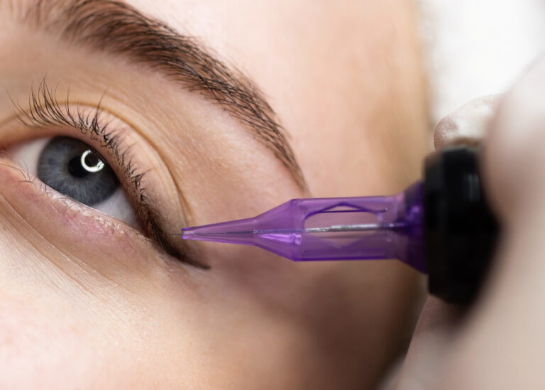 Micropigmentation Concept. Beautician doing permanent make up eyeliner procedure to young woman, closeup of attractive female getting pmu treatment in beauty studio, artist using tattoo pen machine